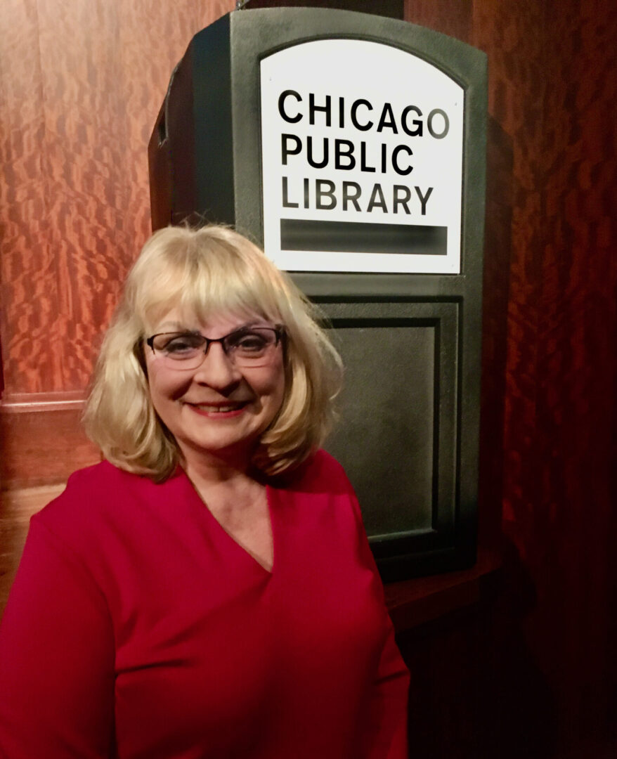 A woman standing in front of a public library sign.